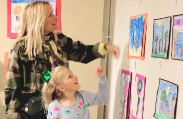 mother and daughter look at student art submissions