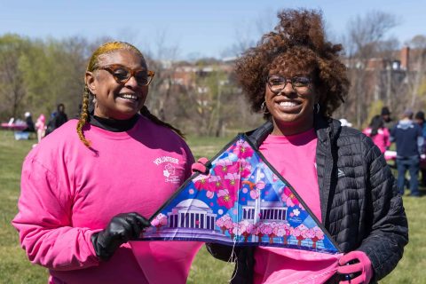 Happy volunteers holding a 2024 official kite