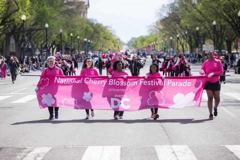 Volunteers at Parade holding the Festival banner